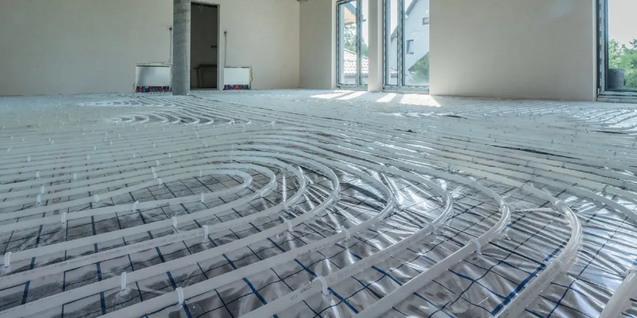 Instalacja ogrzewania podłogowego w nowym domu. Rury ułożone na folii izolacyjnej, gotowe do zalania betonem. To przyszłe oszczędności na koszt ogrzewania podłogowego.
