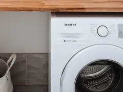 Biała pralka Samsung z technologią Digital Inverter. Obok kosz na pranie.