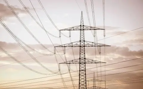 Linie energetyczne mwh przecinają niebo, tworząc geometryczny wzór na tle chmur.