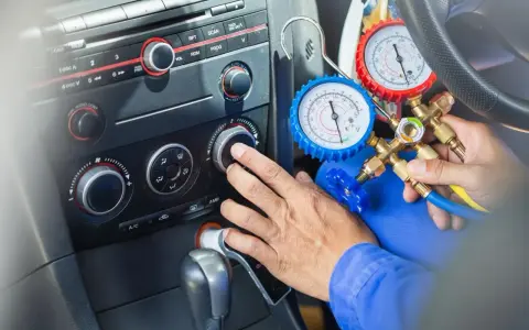 Mechanik sprawdza ile czynnika do klimatyzacji pozostało w samochodzie, używając manometrów.