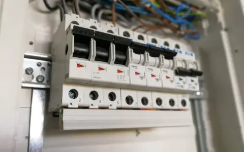W rozdzielnicy elektrycznej widać rzędy bezpieczników automatycznych, każdy oznaczony numerem, np. c16.