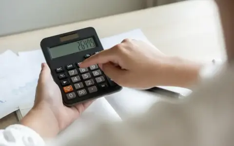 Ręce liczą na kalkulatorze kwotę 26475, być może to opłata OZE.