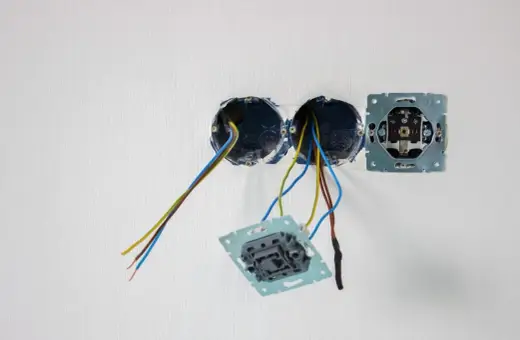 Rozpoczęte osadzanie puszek elektrycznych. Widać przewody wychodzące z dwóch puszek, a obok zamontowany mechanizm gniazdka.