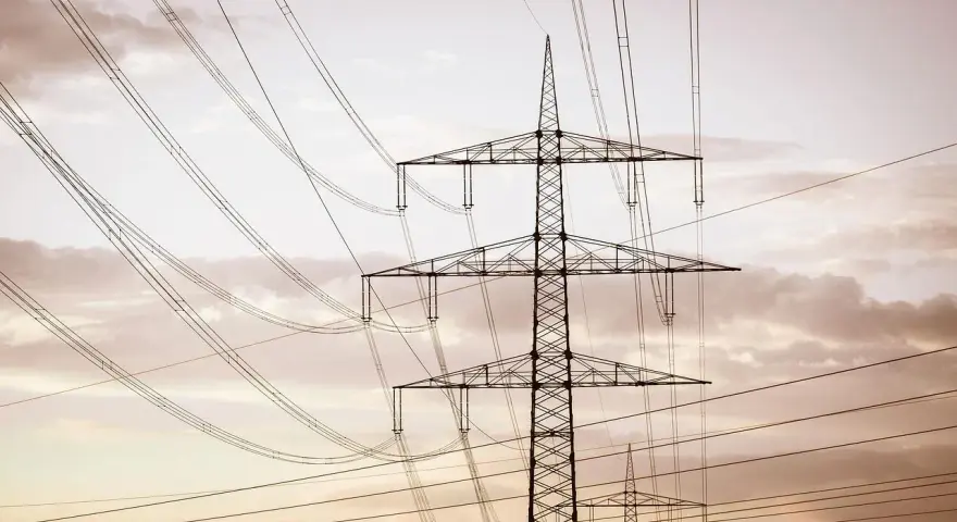 Linie energetyczne mwh przecinają niebo, tworząc geometryczny wzór na tle chmur.
