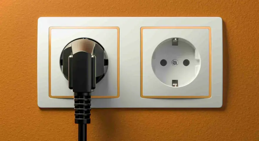 Dwa gniazdka elektryczne na pomarańczowej ścianie. Jedno z nich jest puste, drugie z wtyczką. Zastanawiasz się, jakie gniazdka w Egipcie?