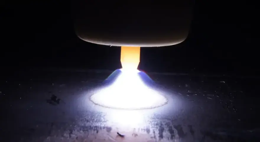 Jasny, gorący łuk elektryczny rozświetla ciemność, topiąc metal.