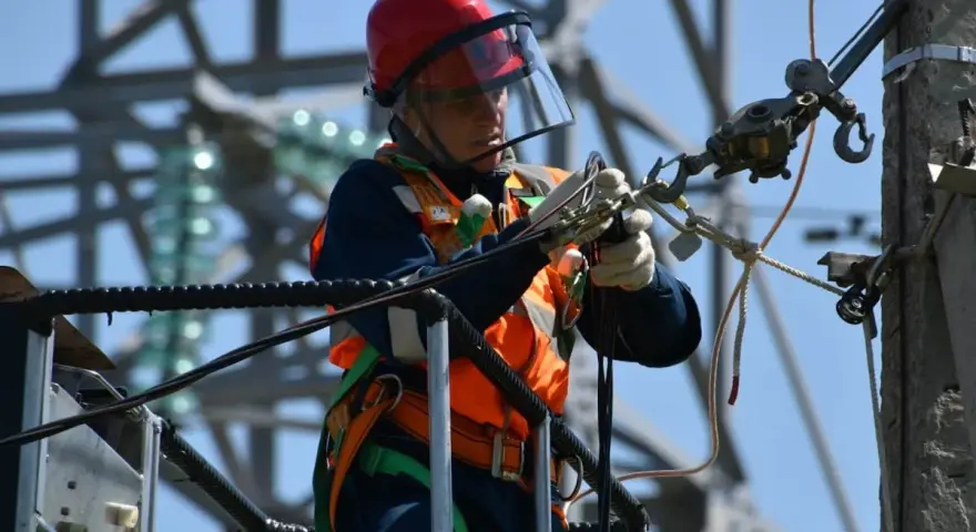 Elektryk w kasku i kamizelce pracujący na wysokości. Zastanawiasz się, ile zarabia elektryk? To praca wymagająca i odpowiedzialna.